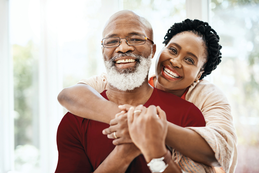 A woman hugging a man from behind.