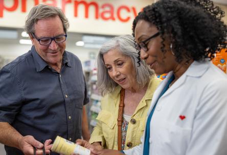 A couple looking at medicine with a pharmacist.