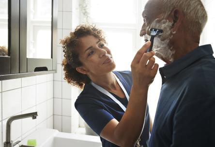 Caregiver helping man shave 