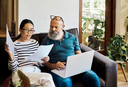 Man and woman looking at papers and laptop at home