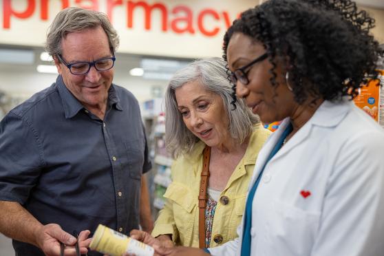 A couple looking at medicine with a pharmacist.