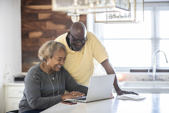 An older black couples looks at a laptop