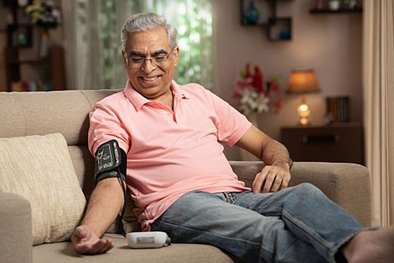 A senior uses a blood pressure monitor at home