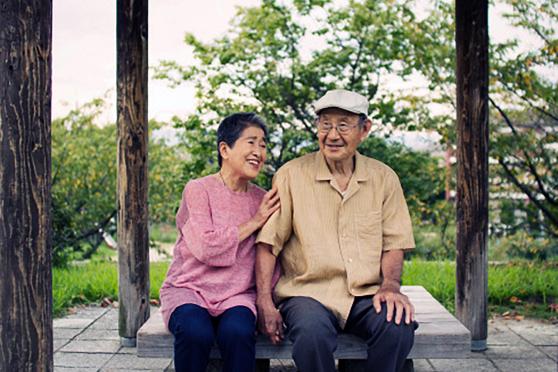 Two seniors sit on a bench outside